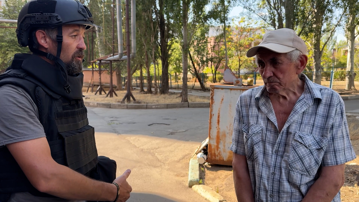 Максим уговаривает местного жителя выехать из опасного района. Фото: Дарья Литовченко / «Новости Донбасса»