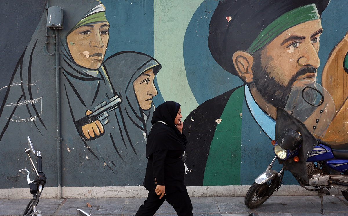 Иранская женщина проходит мимо настенной картины с изображением иранских революционных солдат в Тегеране, Иран, 25 февраля 2026 года. Фото: Abedin Taherkenareh / EPA