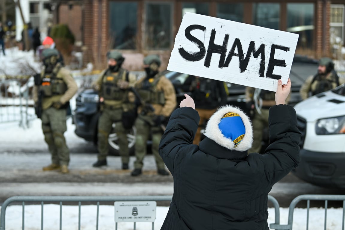 Участница акции держит плакат с надписью «позор» на месте стрельбы в Миннеаполисе, США, 7 января 2026 года. Фото: Craig Lassig / EPA