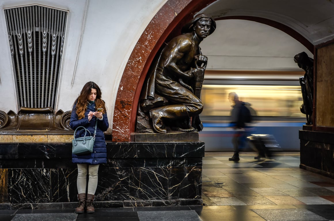 A woman looks at her phone while waiting in the Moscow metro, 16 October 2024. Photo: EPA / Yuri Kochetkov