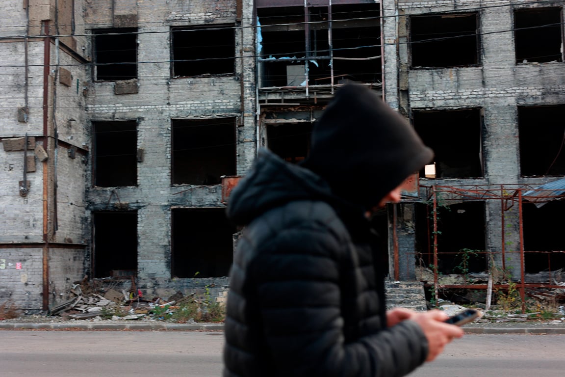 Местный житель на фоне поврежденного жилого дома в Левобережном районе Мариуполя, Украина, 8 ноября 2025 года. Фото: Мария Семенова / SIPA / Vida Press / Scanpix / LETA