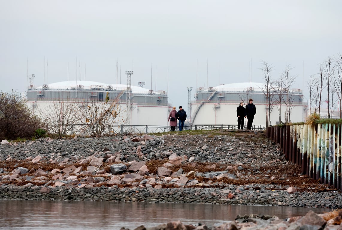 Прохожие на берегу Финского залива на фоне Петербургского нефтяного терминала, 8 ноября 2025 года. Фото: Анатолий Мальцев / EPA