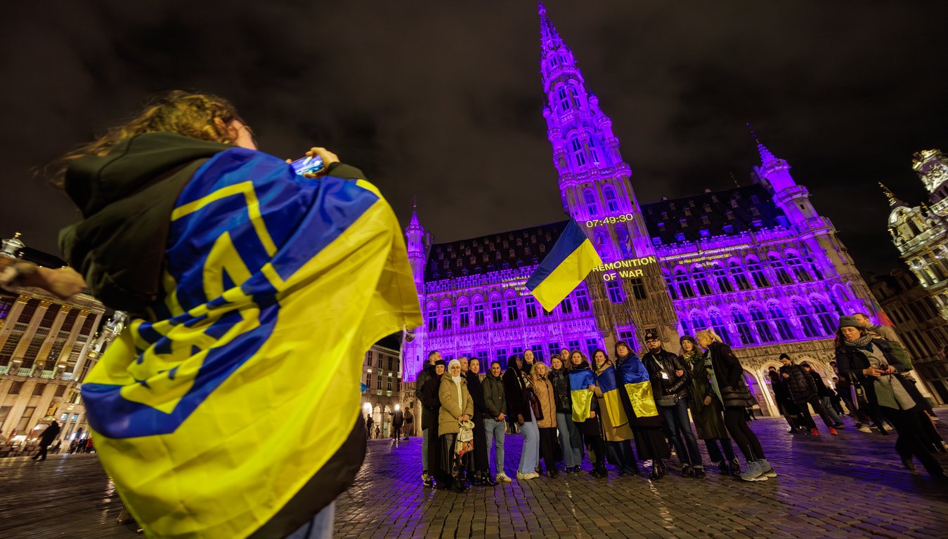 Люди у здания ратуши, подсвеченной в цвета украинского флага, Брюссель, Бельгия, 23 февраля. Фото: Olivier Matthys / EPA