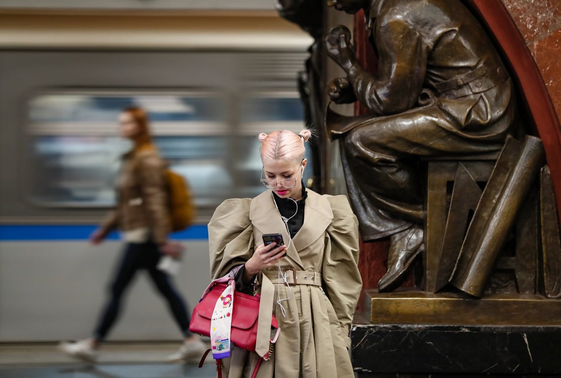 A woman looks at her phone while waiting for a train in the Moscow metro, 19 April 2023. Photo: EPA / Yuri Kochetkov