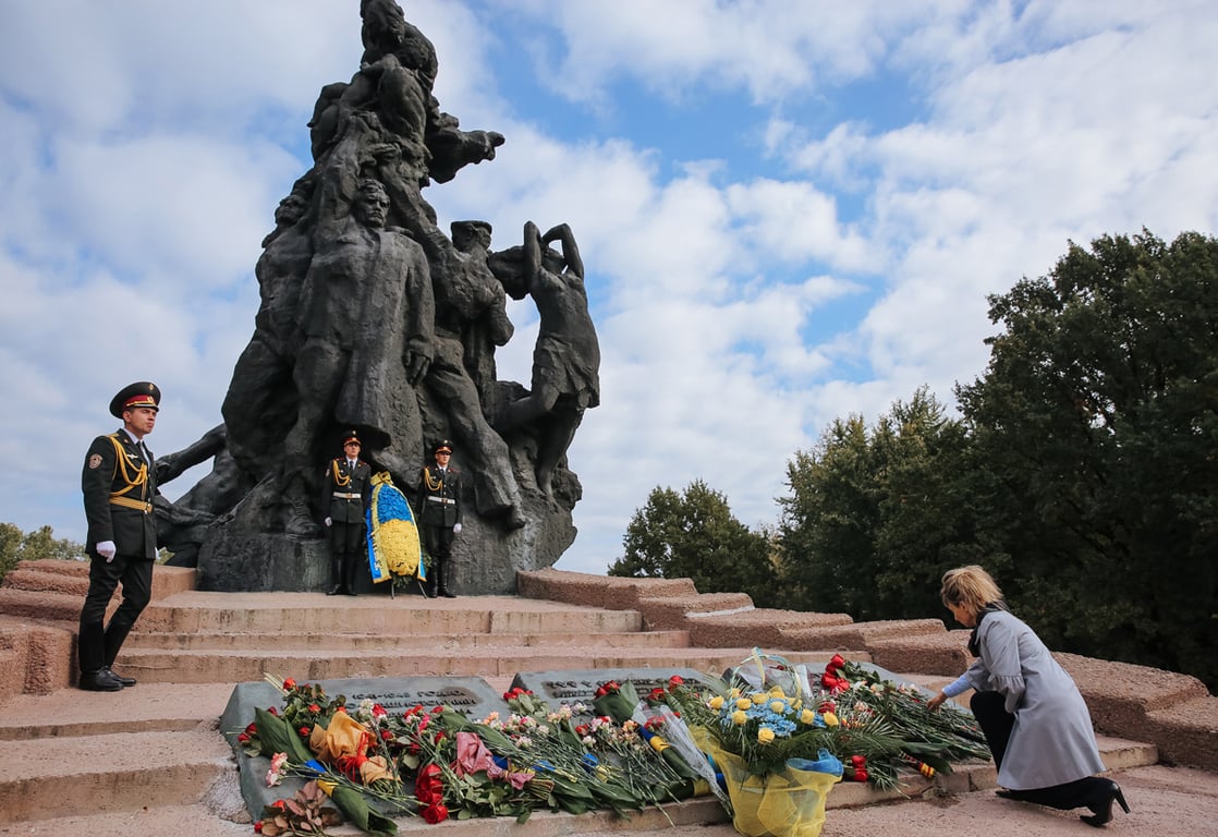 Женщина возлагает цветы у памятника в Бабьем Яру в Киеве, Украина, 29 сентября 2014 года. Фото: Roman Pilipey / EPA