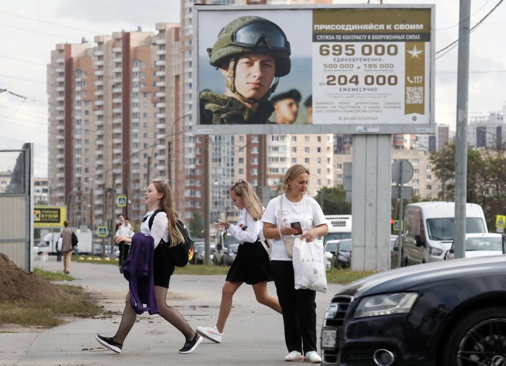 Russian schoolgirls walk past a military conscription poster in St. Petersburg, Russia, 1 September 2023. Photo: EPA/ANATOLY MALTSEV