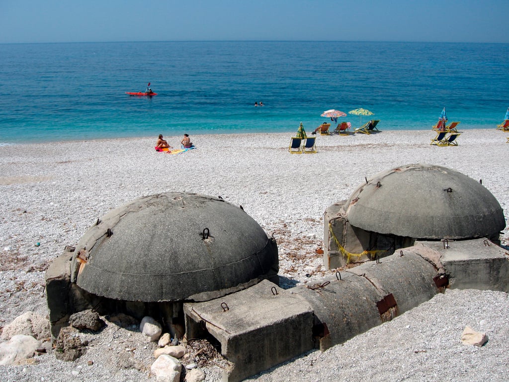 People sunbathe next two two communist-era bunkers on a beach in the Albanian town of Dhërmi, 26 June 2006. Photo: EPA / Armando Babani
