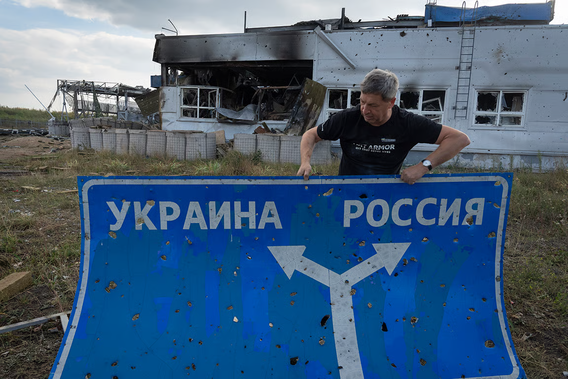 Ukrainian historian Yuriy Savchuk holds a bullet-ridden road sign showing the way to Ukraine and Russia, in the western Russian town of Sudzha. Photo: AP / Scanpix / LETA