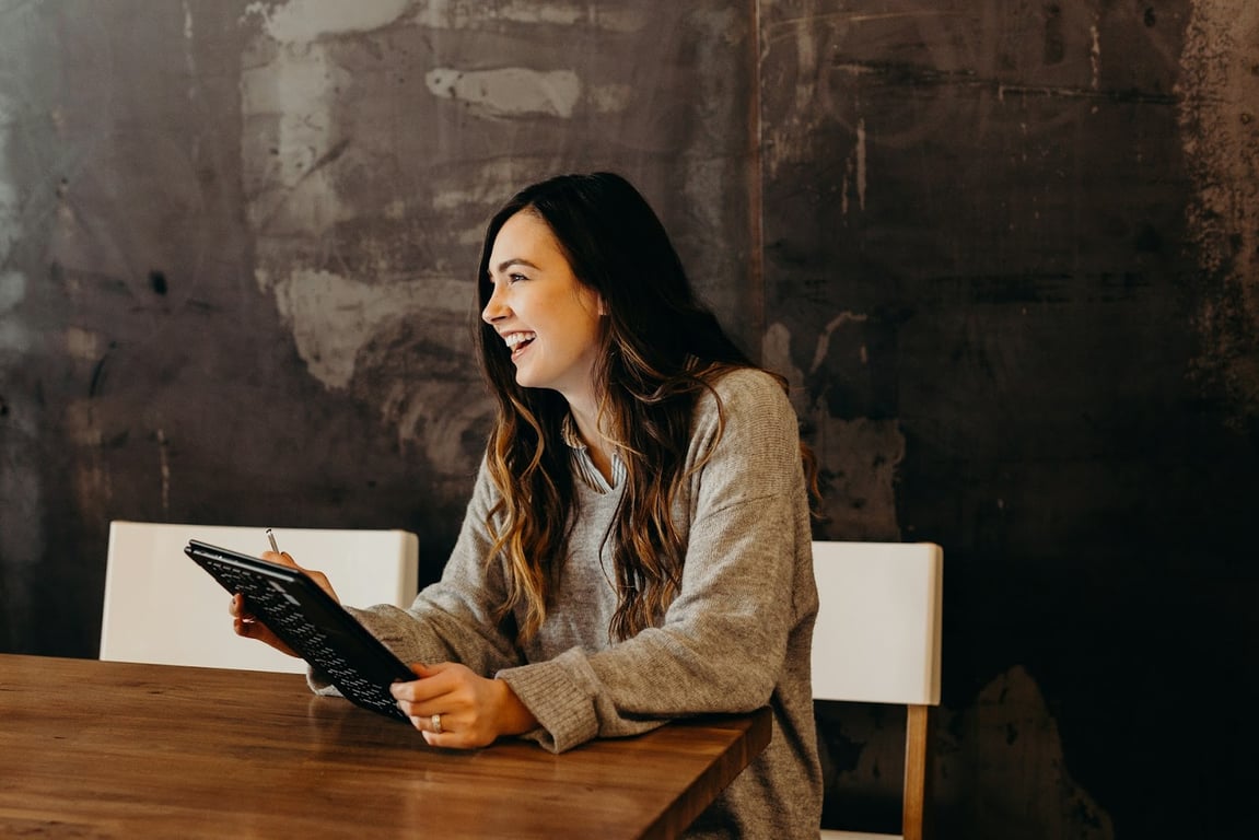 A Gen Z girl sits smiling in an office while holding a tablet