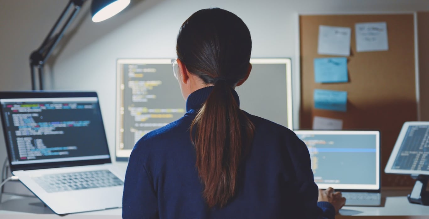 A female recruiter sits looking at screens of data and metrics