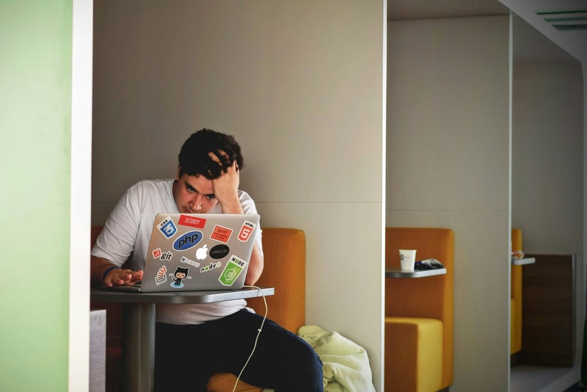 A man sits stressed at a desk on his laptop, representing a challenge