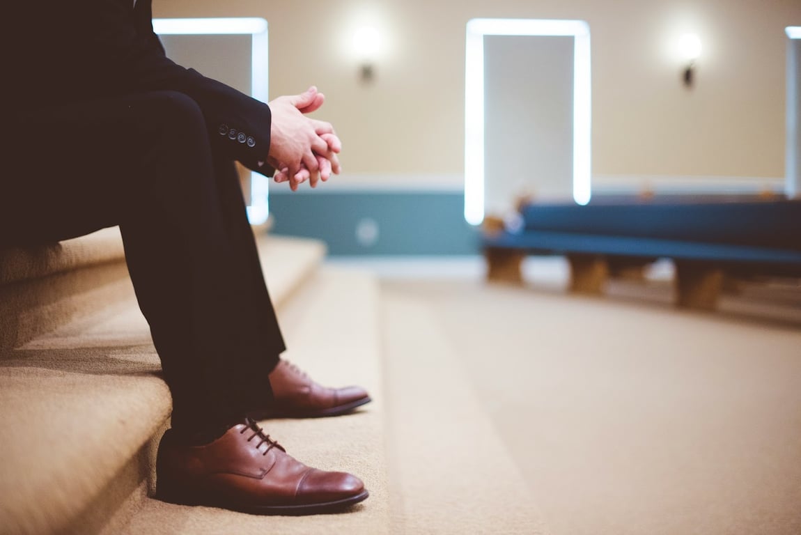 A man in a suit sits waiting in an empty room
