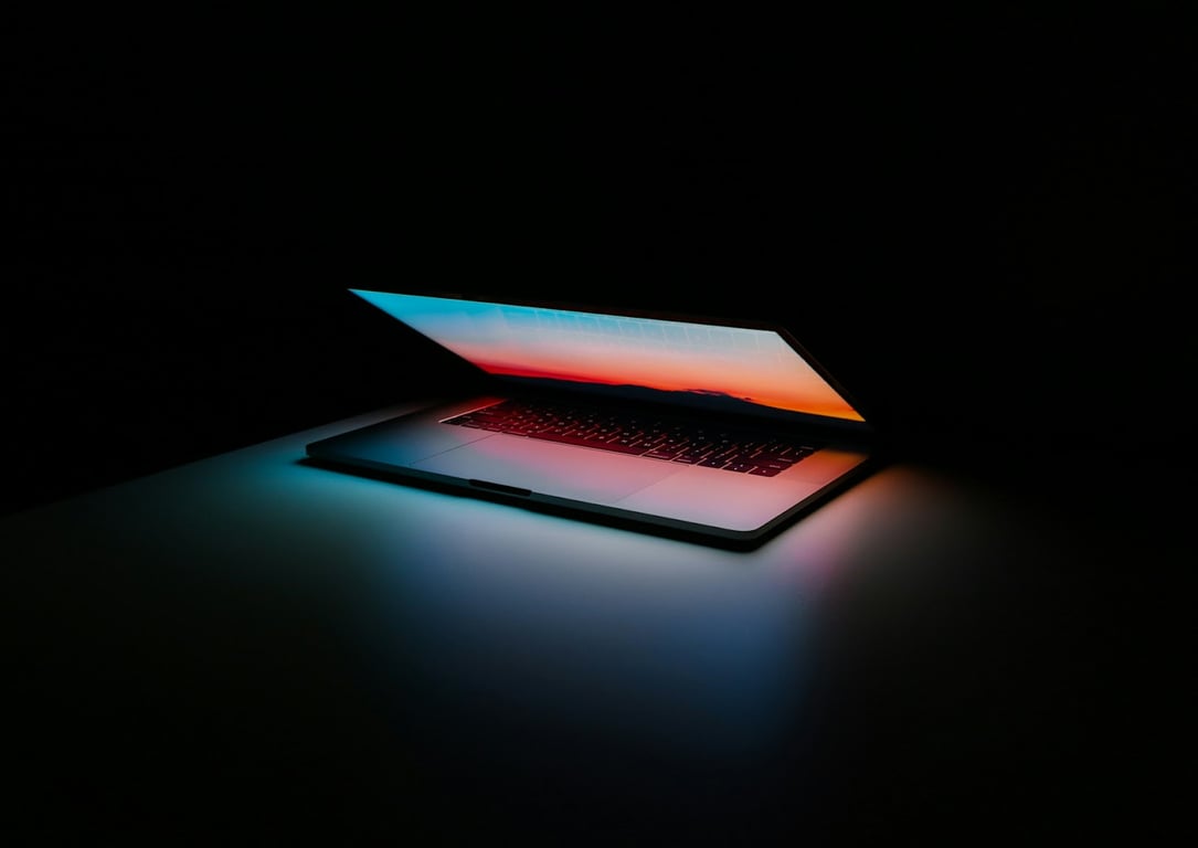 A Macbook opening and showing a bright screen in a dark aesthetic room