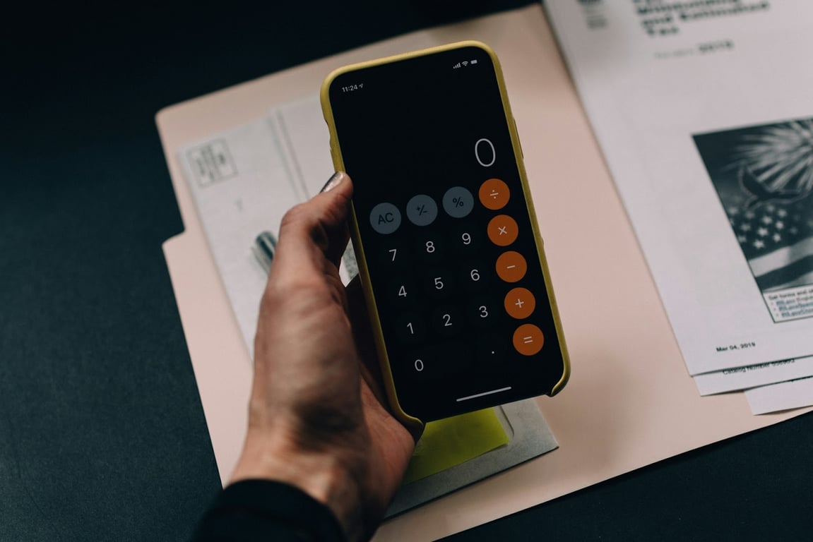 An aesthetic shot of someone holding a calculator of their iPhone while budgeting