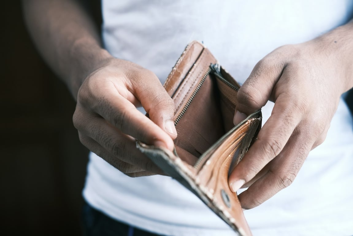 A man looking for money in an empty wallet