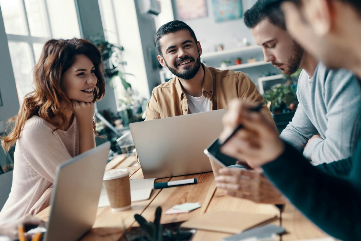 A group of developers smiling while sat around a table