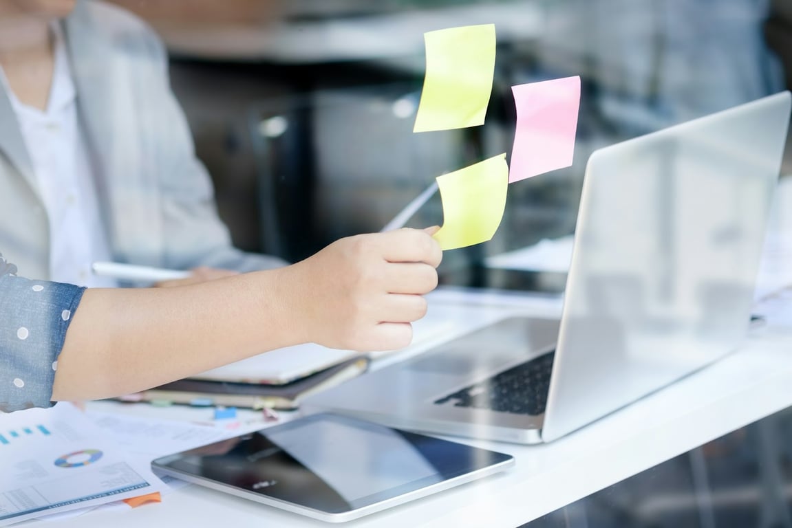 A close-up of someone putting Post-It notes on a glass screen