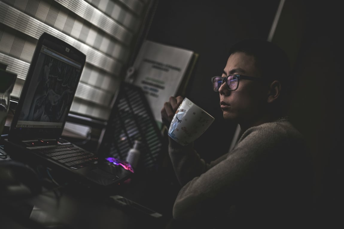 A coder looking sad while drinking coffee at their computer