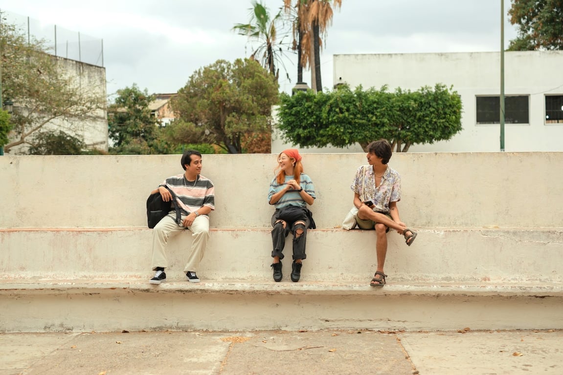 A couple of Gen Z friends sit outside laughing and smiling