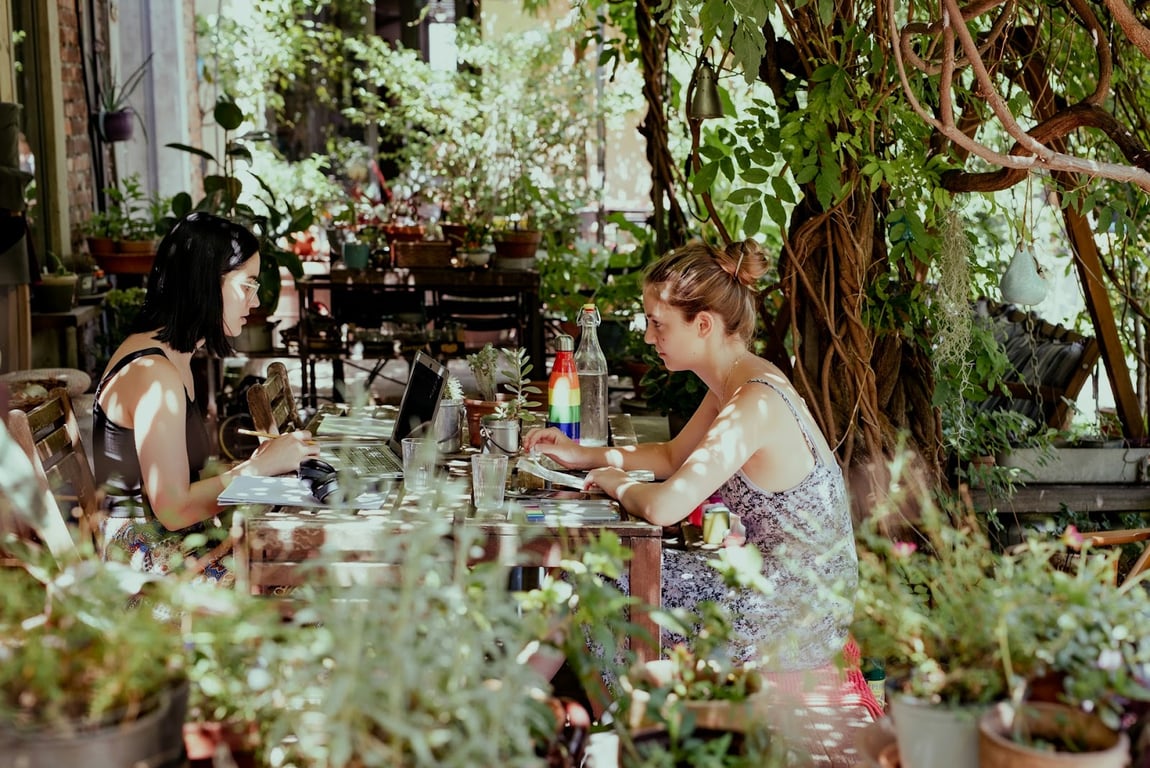 Two female remote workers surrounded by potted plants