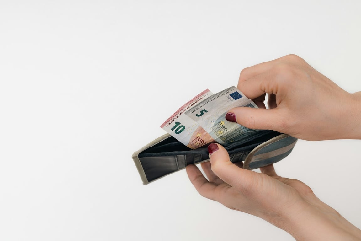 A close up of someone taking two Euro notes out of their wallet