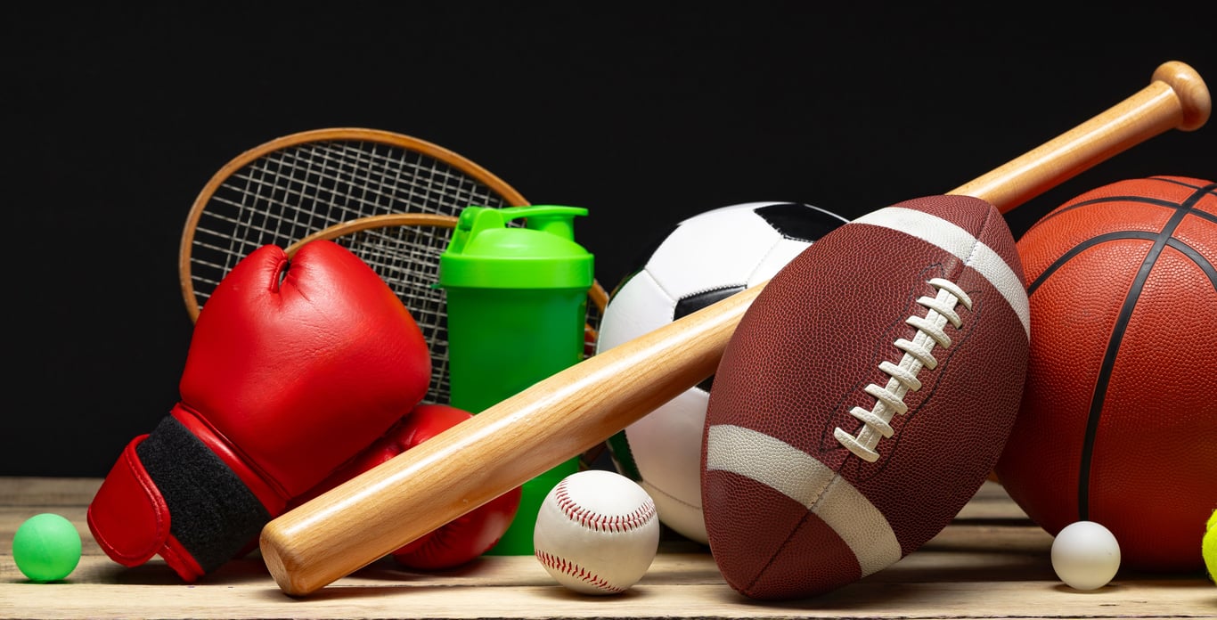 Assorted sports equipment including football, basketball, soccer ball, baseball and bat, tennis racket, and boxing gloves
