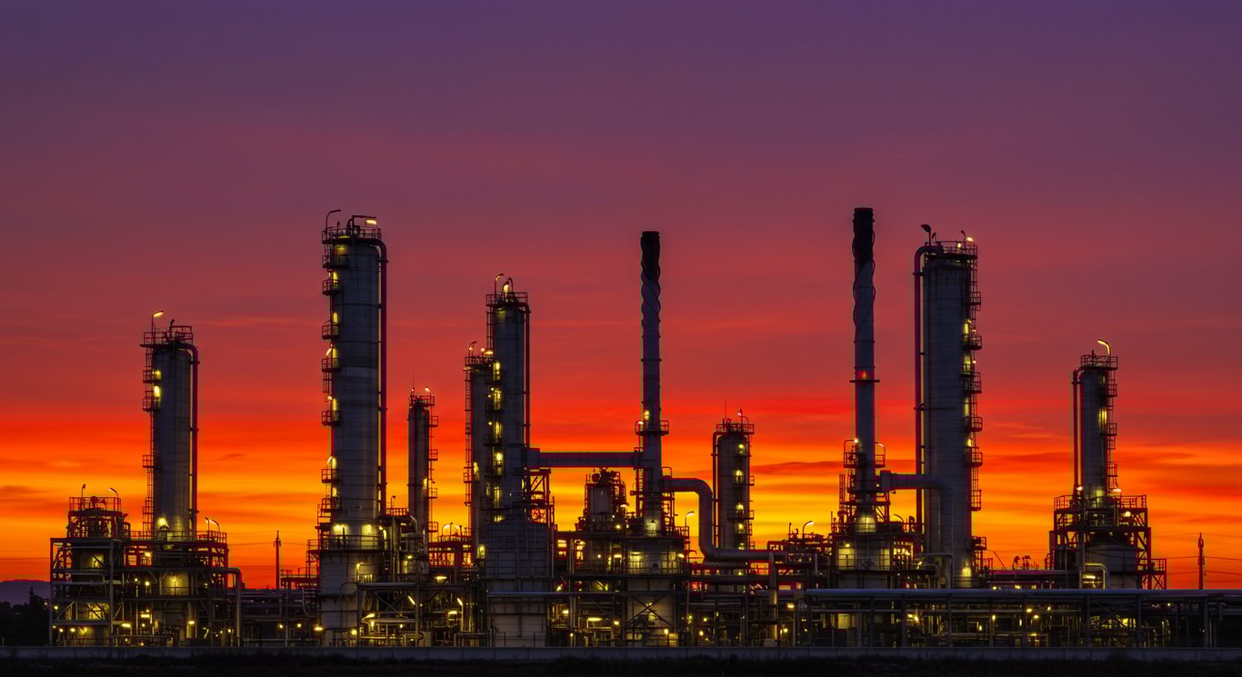 Oil refinery at sunset, symbolizing the energy sector.