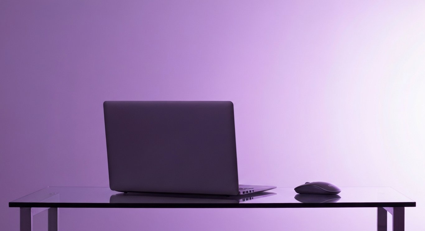 Laptop on clean glass desk with soft purple gradient background