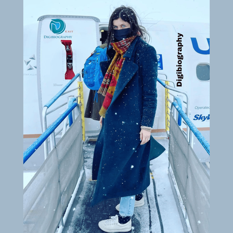 Alexandra Daddario stands out of the door of an airplane in the snowfall