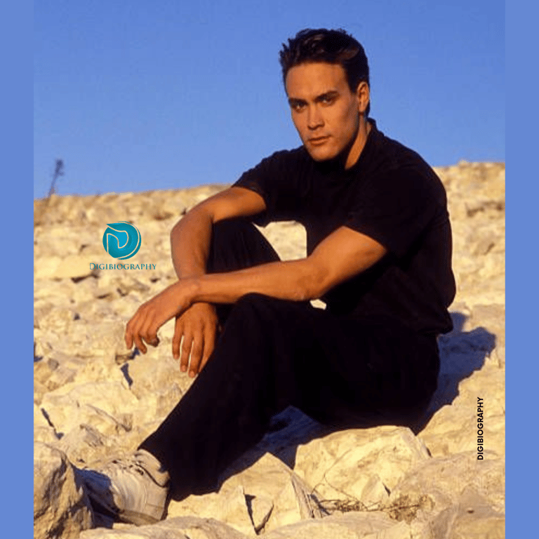 Brandon Lee sitting on stone while wearing a black t-shirt and jeans