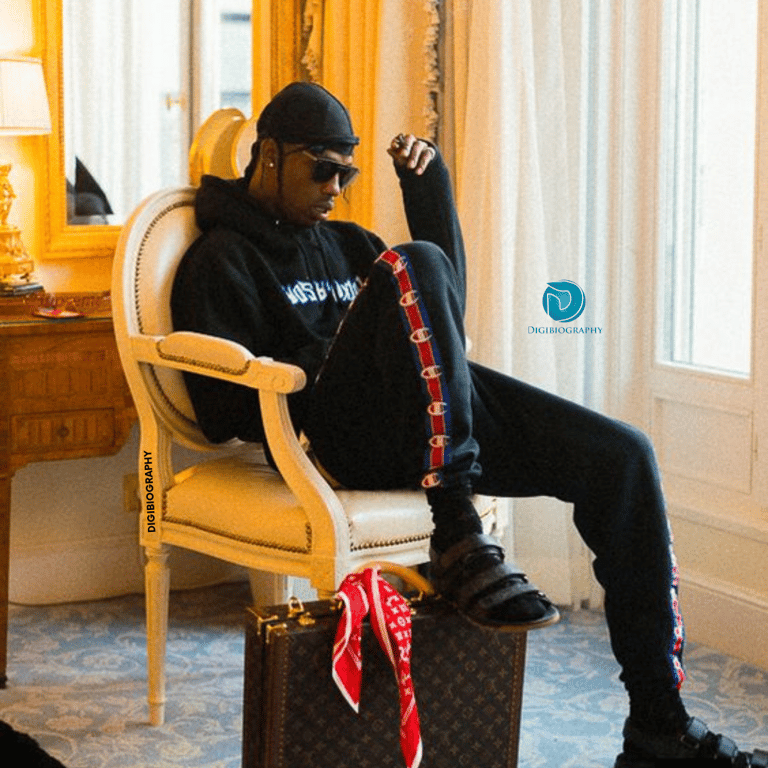 Travis Scott sitting on the chair and wearing a black hoodie