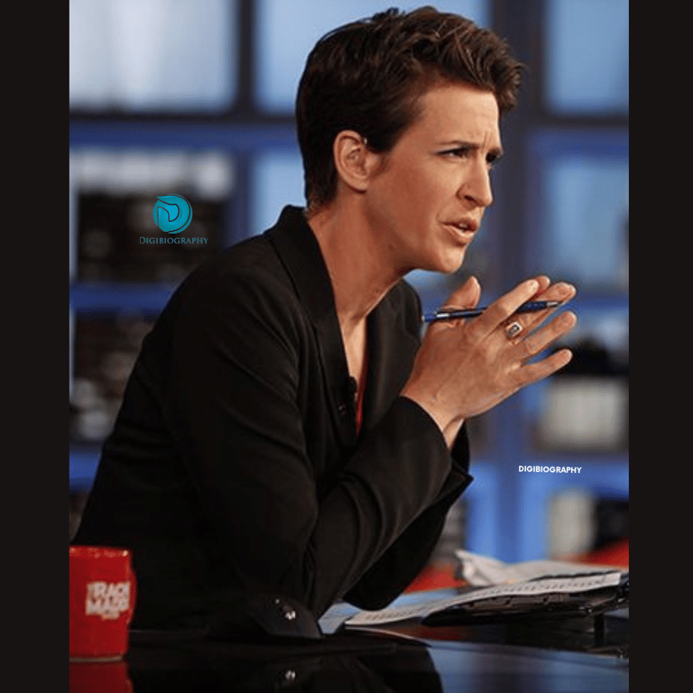 Racheal Maddow sitting on her show and gives a side look