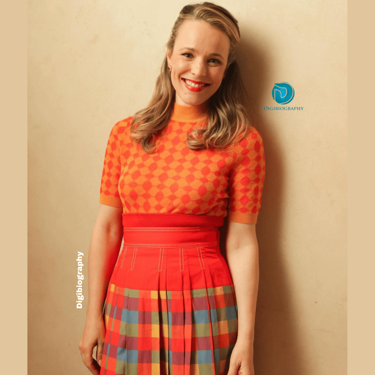 Rachel McAdams stand close to the wall and wears a orange dress