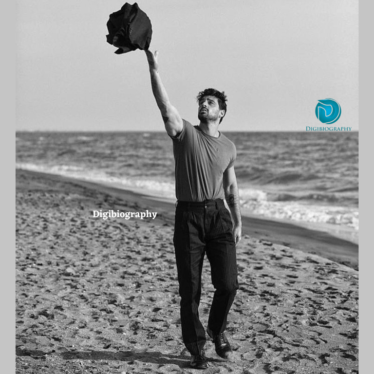 Michele Morrone throws a black shirt in the air at the beach