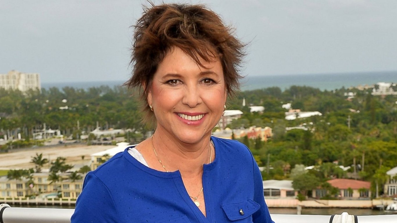 Kristy McNichol wearing a blue top and stands in the terrace of the house