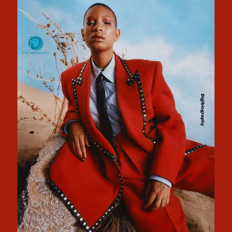 Willow Smith wearing a red suit and sitting on the rock