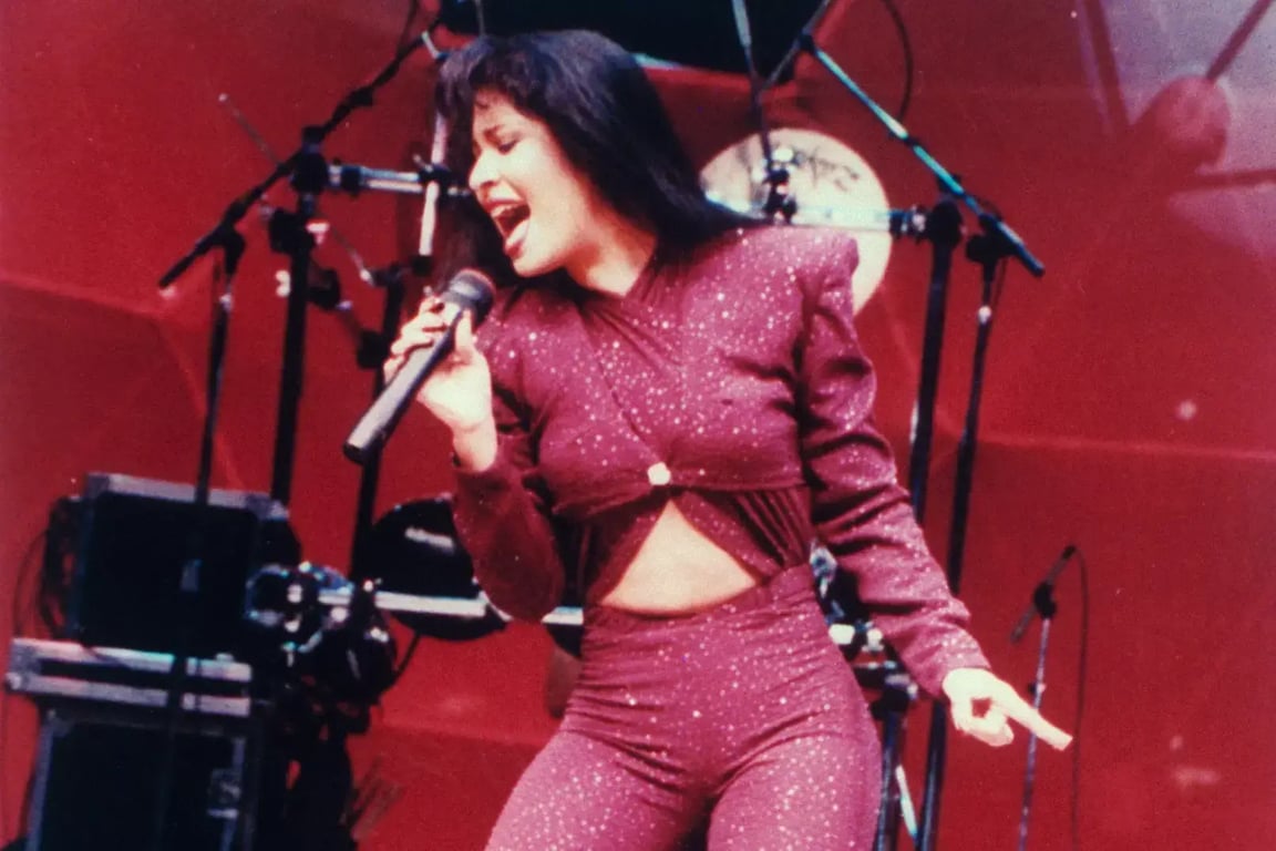 Selena Quintanilla singing a song on a stage in a red dress 