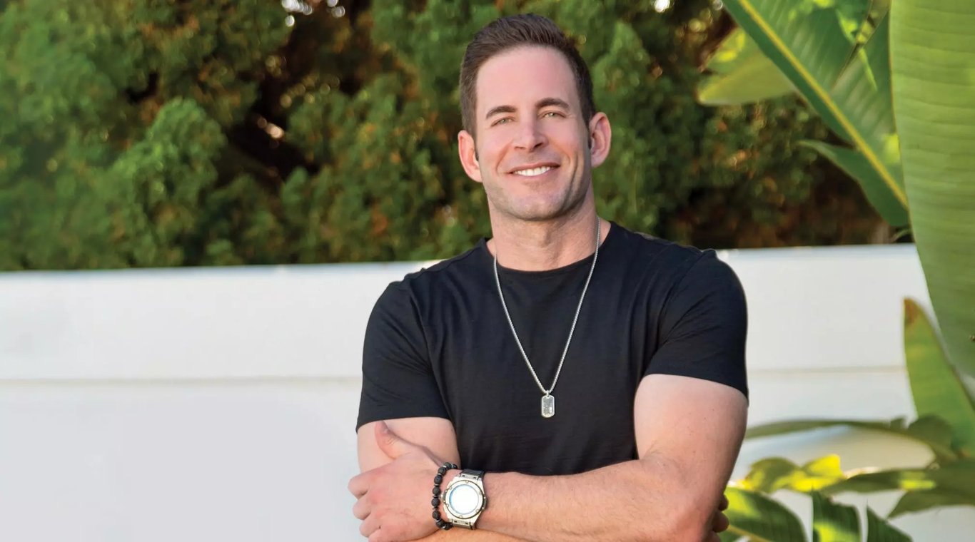 Tarek El Moussa standing in a black t-shirt with the locket on their neck 