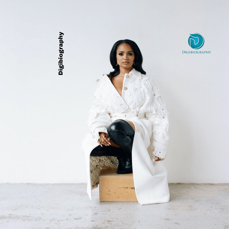 Kyla Pratt wears a white long court with black long boots and sits on the box