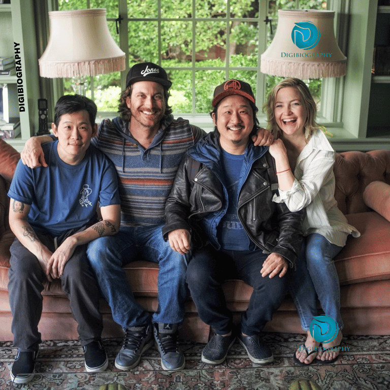 Bobby Lee sitting with her friend while wearing a black jacket and blue t-shirt