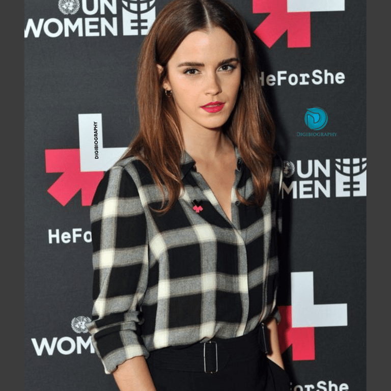 Emma Watson stands on the floor while wearing a check shirt and black jeans