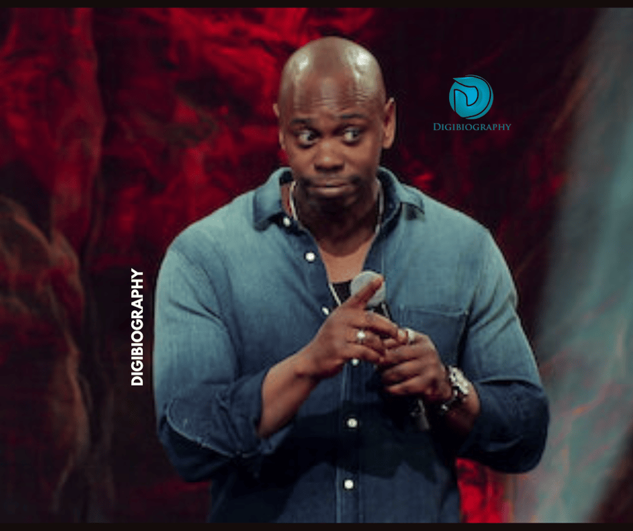 Dave Chappelle wearing a green shirt while taking a mic and saying something to her audience