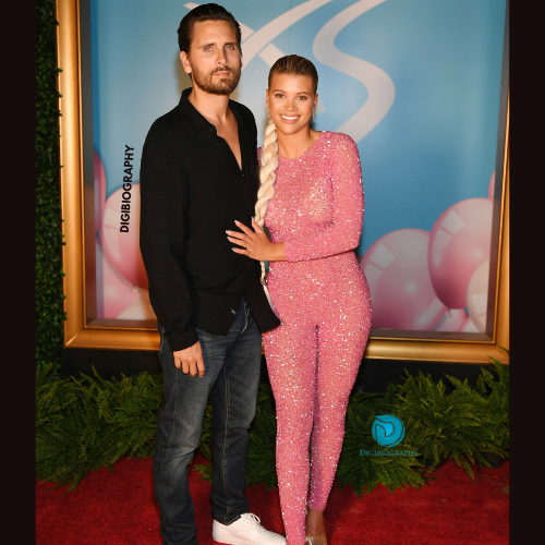 Scott Disick stands with her girlfriend and wearing a black shirt and black jeans