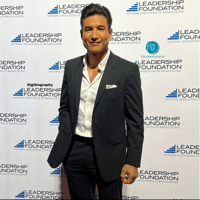 Mario Lopez wearing a black coat and while gives a pose