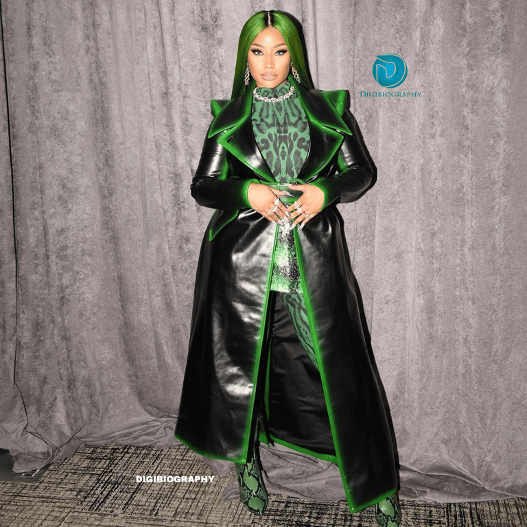 Nicki Minaj stands in the room while wearing a black with a green light jacket