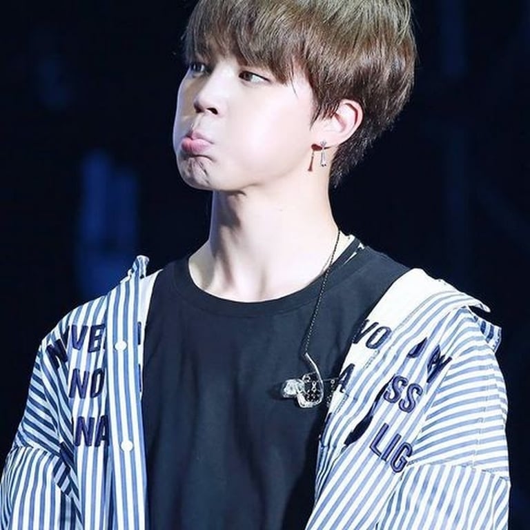 Park Jimin makes a funny face and wearing a black t-shirt and white open shirt
