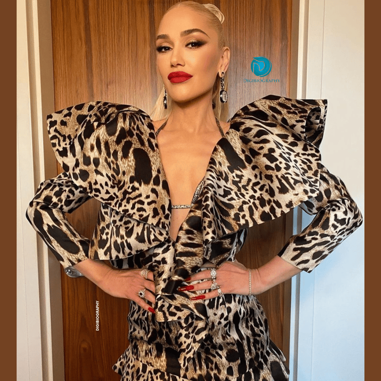 Gwen Stefani wearing a white-orange and black print dress while standing on the floor