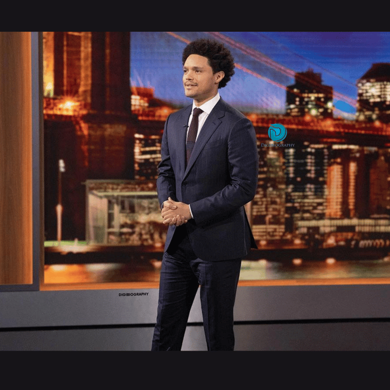 Trevor Noah wearing a black coat and stand on the stage