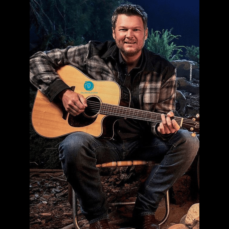 blake shelton singing holding his guitar while wearing a white and black print jacket