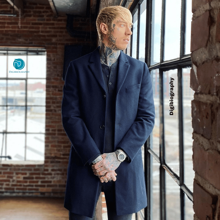 Trace Cyrus stand close to the window and looked outside while wearing a blue suit